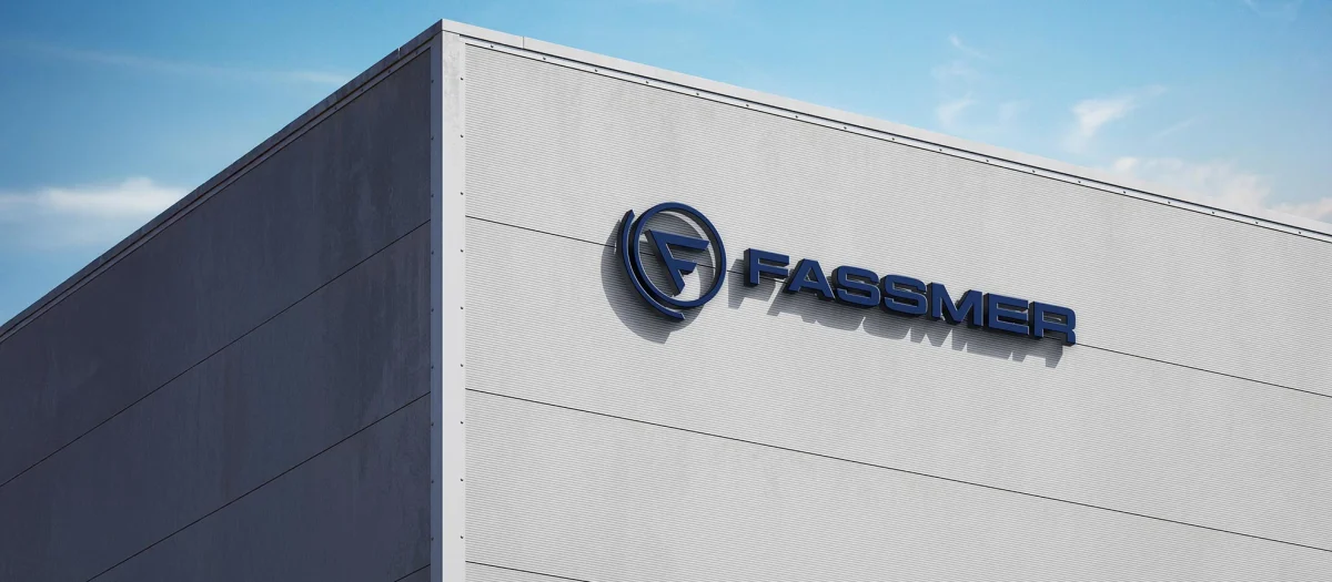 Fassmer company building in Berne with blue Fassmer logo on the facade against a blue sky.“