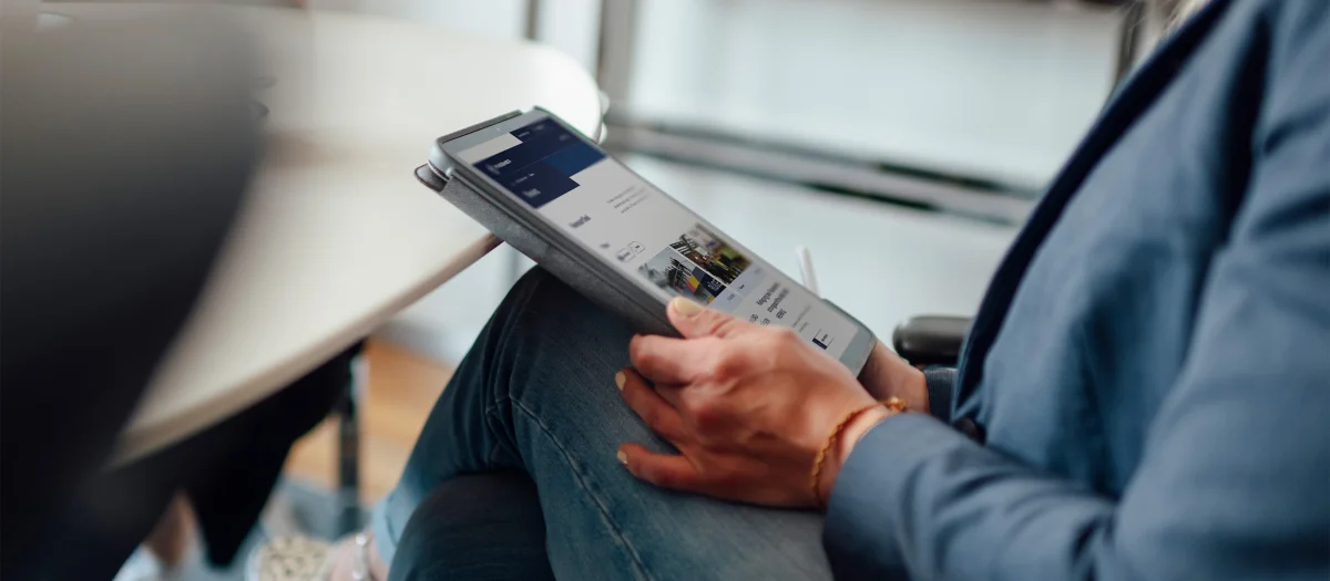 Person at Fassmer in a meeting: close-up of a hand holding a tablet with a website open – modern digital work in the office.