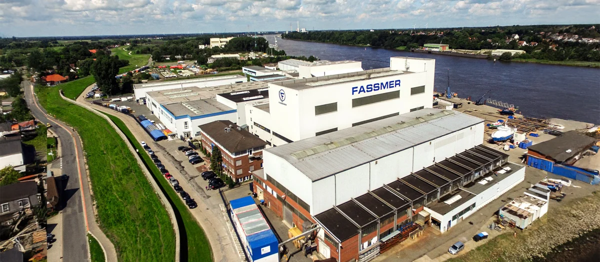 Aerial view of the Fassmer shipyard in Berne on the Lower Weser River. The image shows the modern production halls and waterfront facilities where ships and specialized vessels are built.