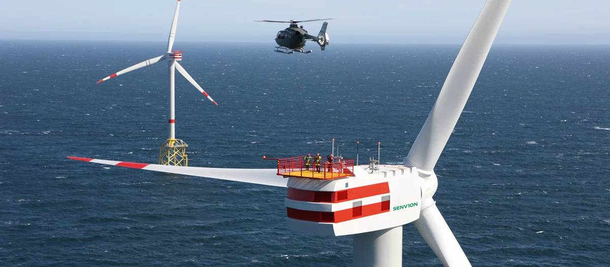 Offshore wind turbine by Senvion with a helicopter approaching above the North Sea. Fassmer produces the composite components for the nacelle and spinner, contributing to sustainable energy technologies.