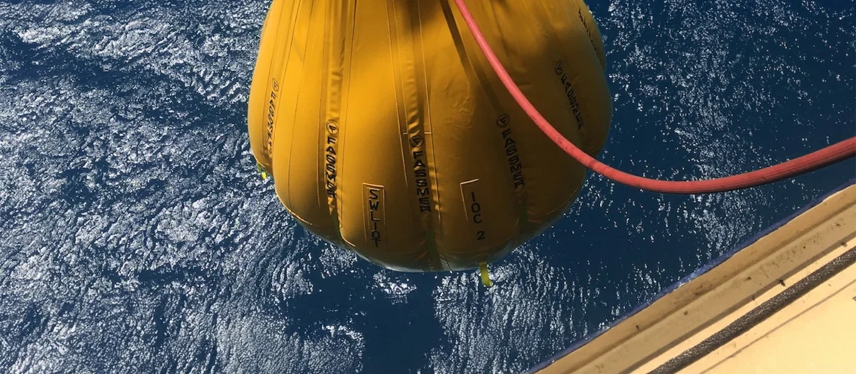 Fassmer Service load test with water bag – yellow test weight for safety and maintenance of maritime equipment above the sea.