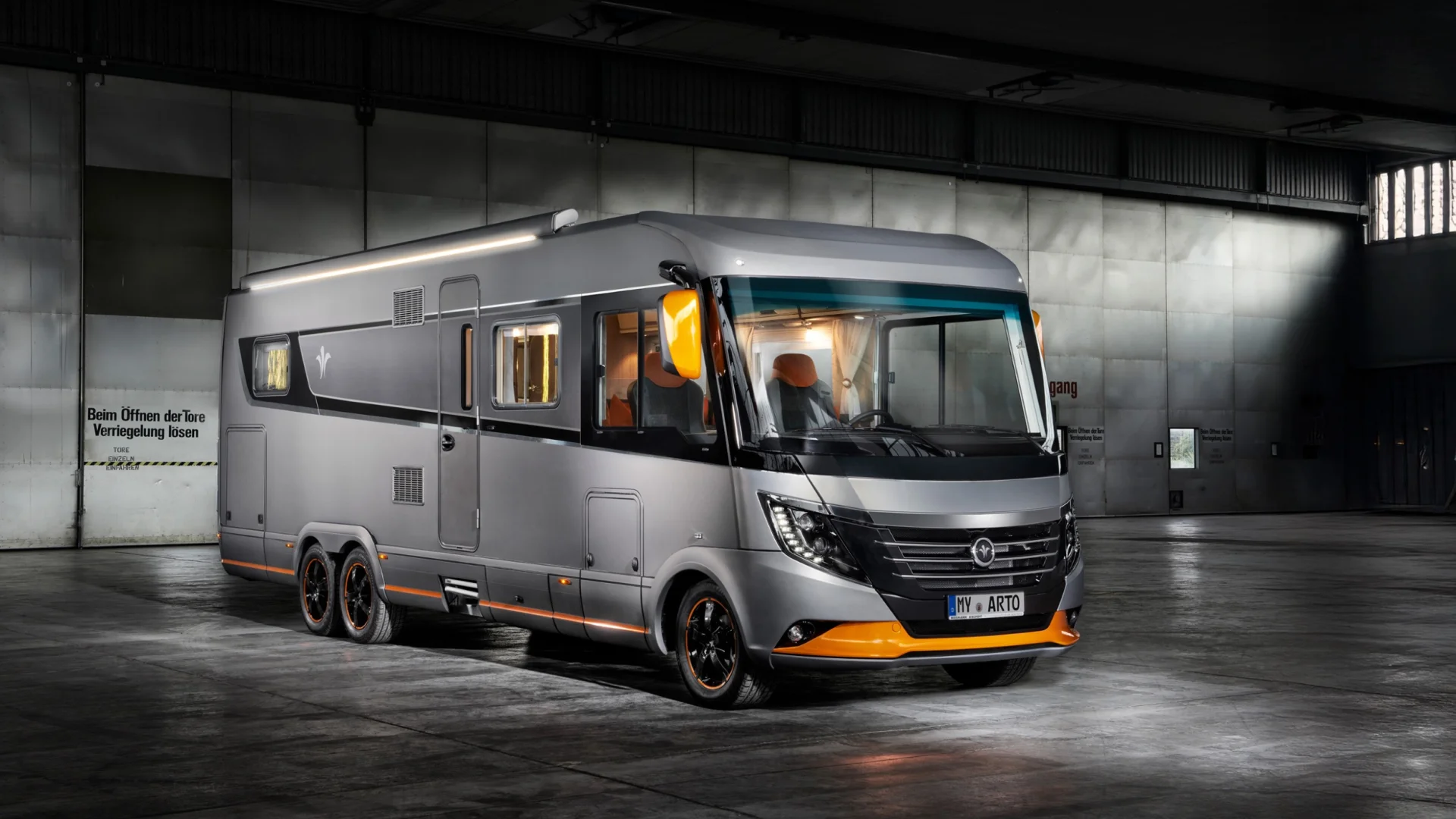 Photo of a modern Niesmann+Bischoff Arto motorhome in a hall, grey design with orange accents.