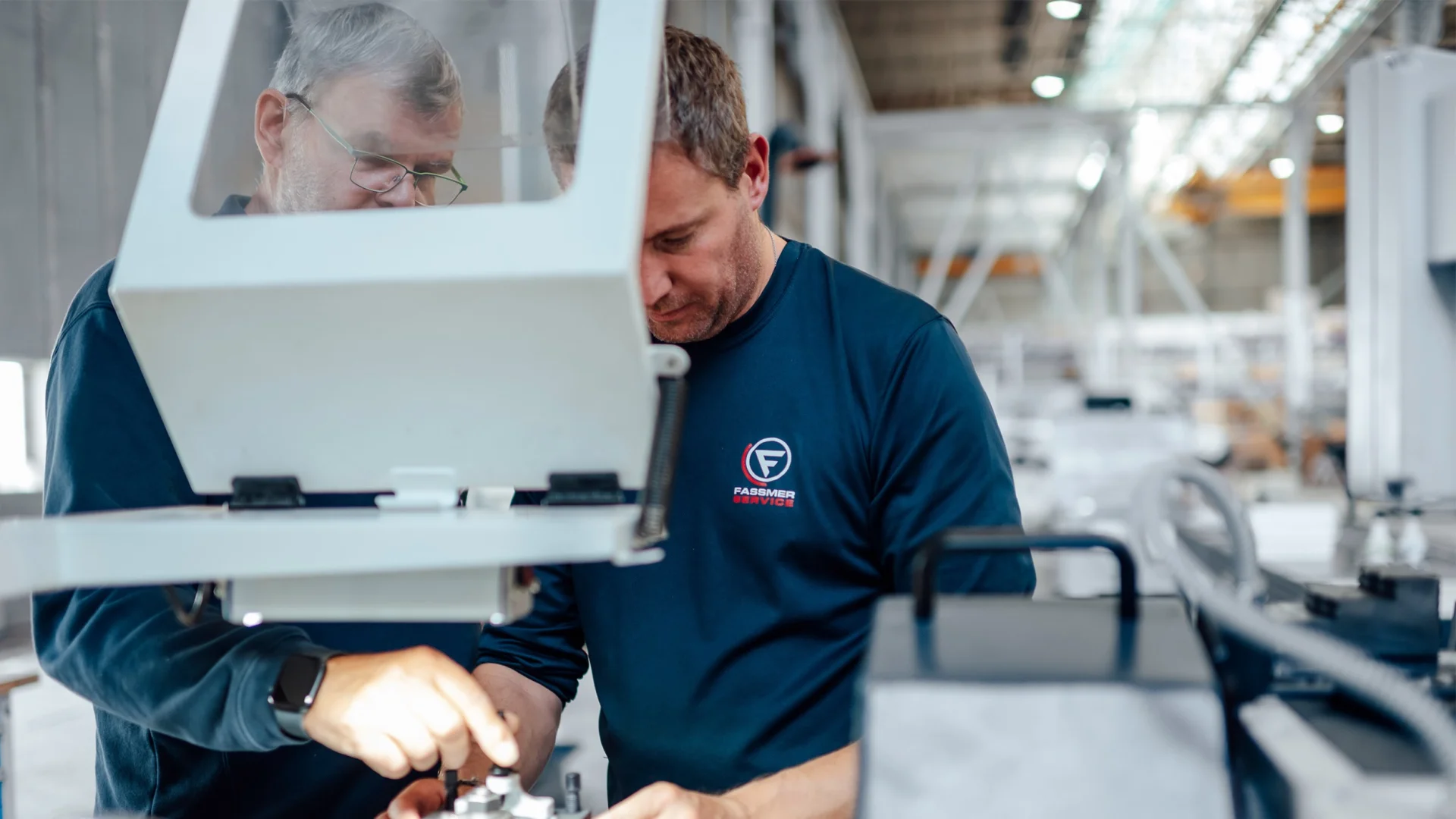 Fassmer Service employees during quality control: Two technicians carefully inspecting components in the workshop.