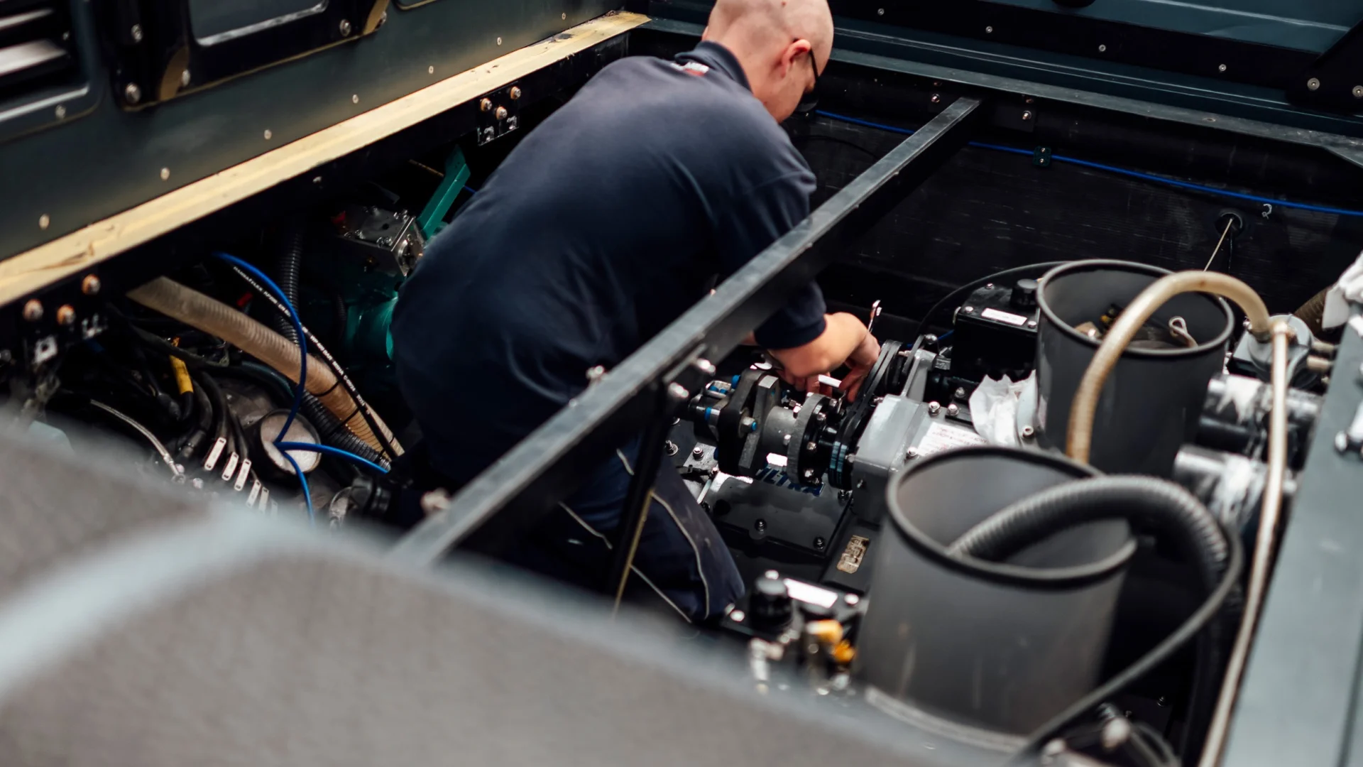Photo of a Fassmer service employee working in the engine room of a boat, performing repairs on engine and drive components.