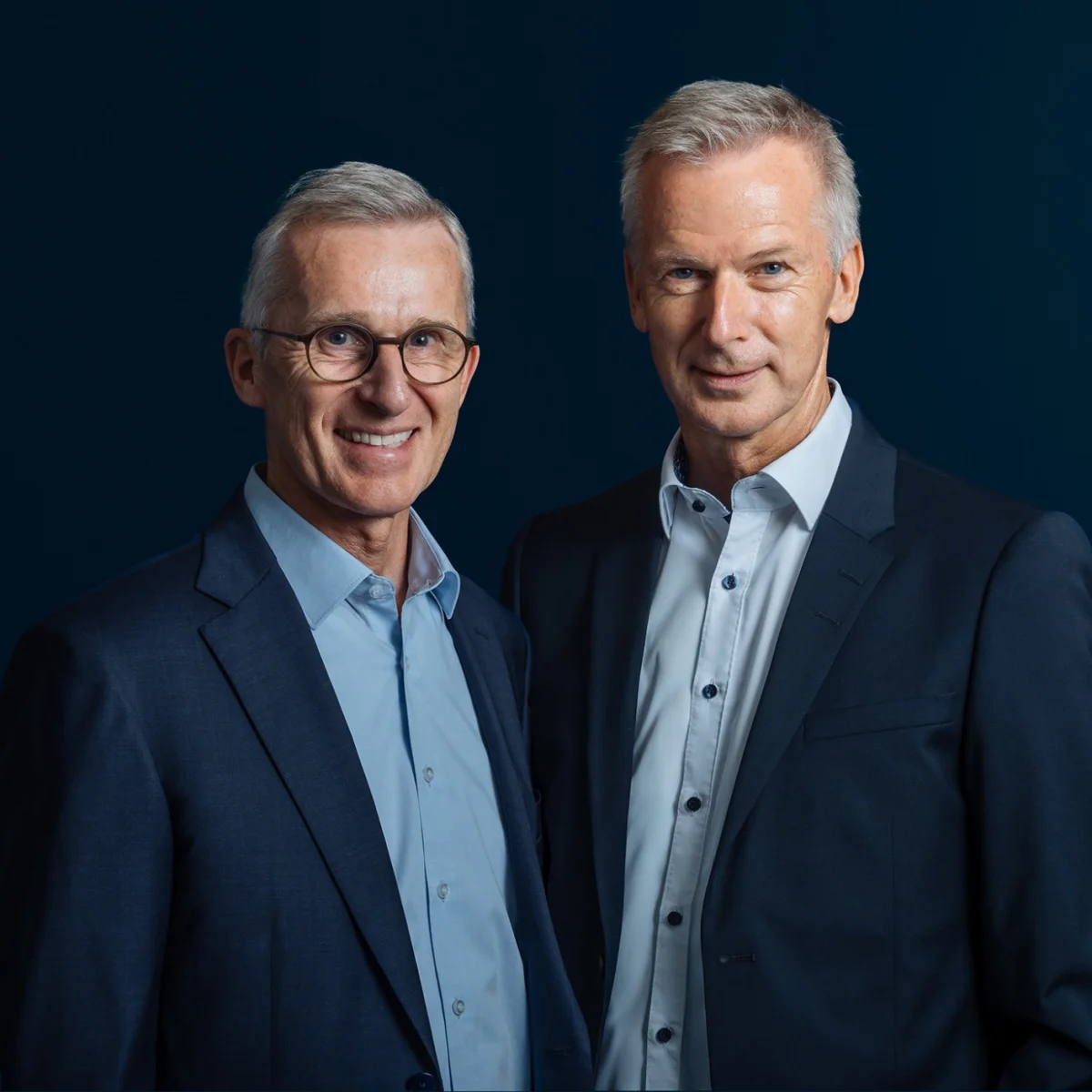 Portrait of Holger and Harald Fassmer, management of the Fassmer Group – both wearing suits against a dark background.