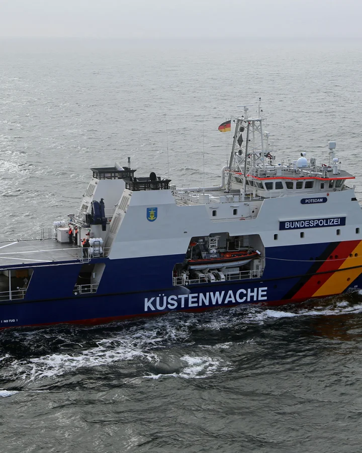 An 86-metre offshore patrol vessel of the German Federal Police with helicopter landing platform at sea; a Federal Police helicopter approaches the deck of the coast guard vessel “Potsdam”.