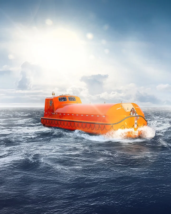 Fassmer offshore lifeboats at sea: Two enclosed orange rescue boats navigating the waves under bright sunlight.